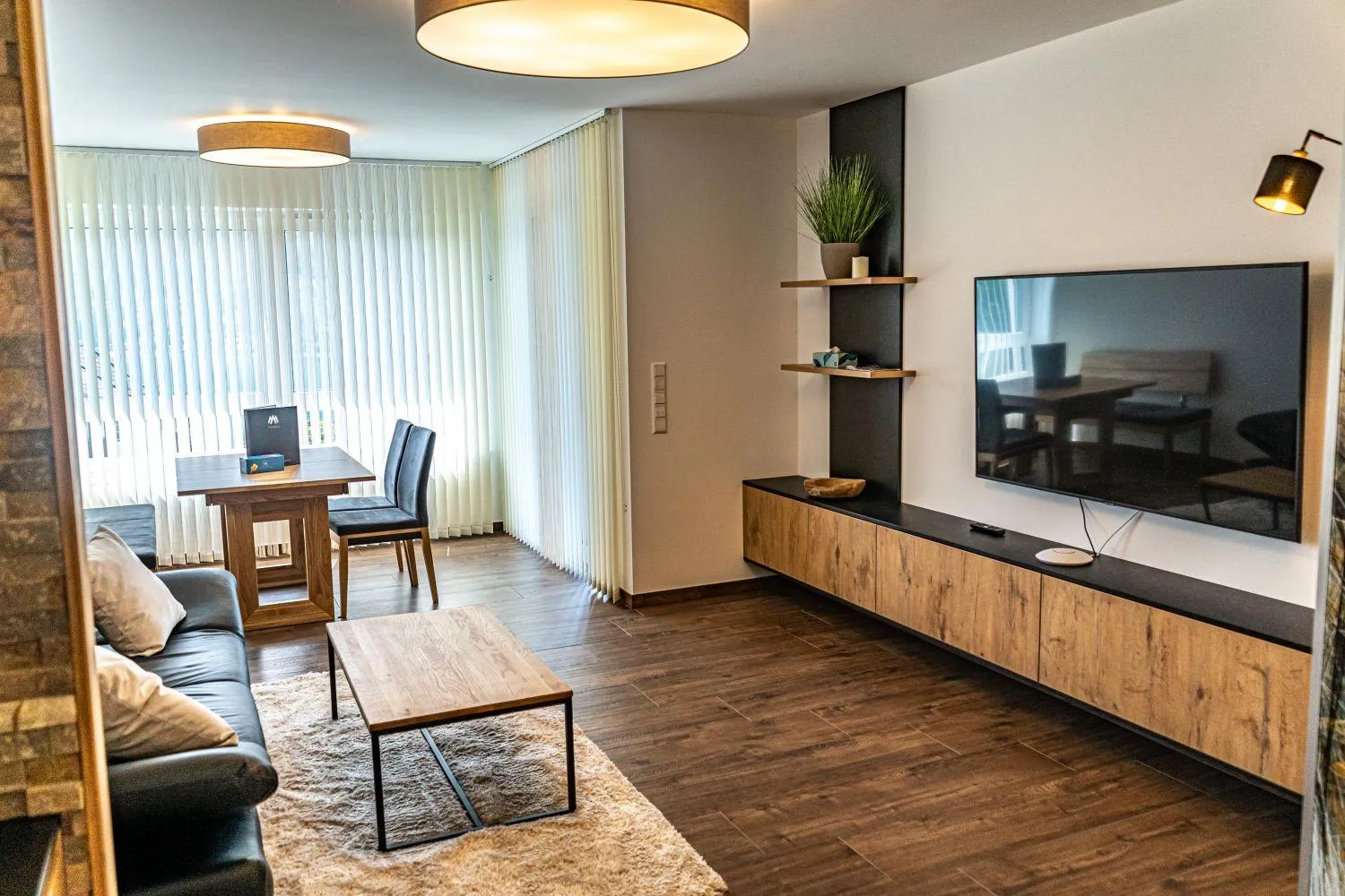 Modernes Wohnzimmer mit TV, Schreibbereich und heller Einrichtung
