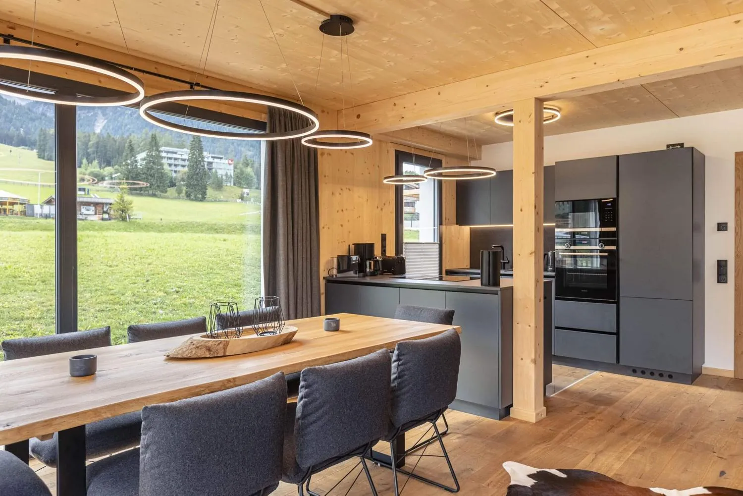 Offene Wohn- und Esszimmer mit moderner Küche, Holztisch und Bergblick