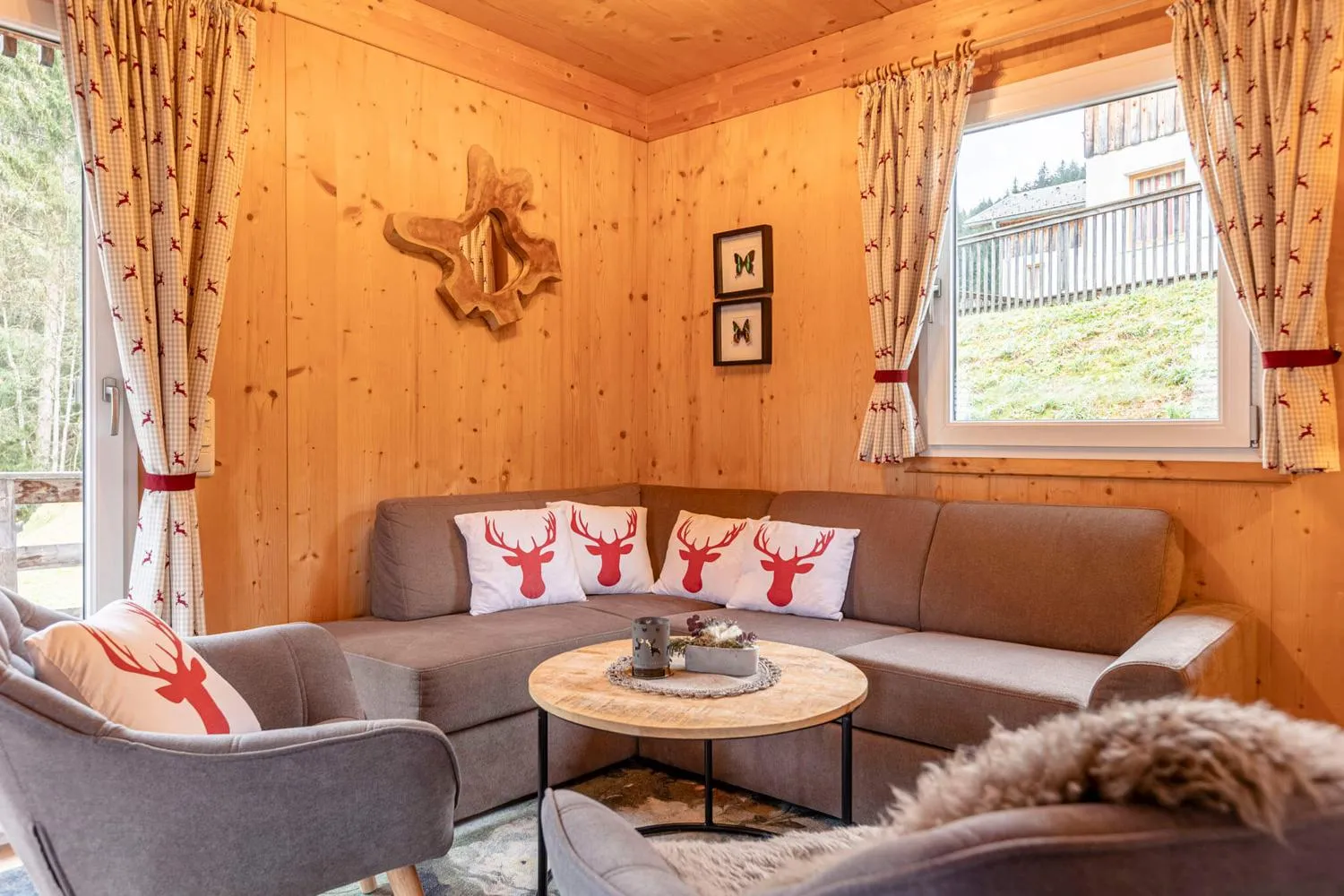 Berghütten-Wohnzimmer mit grauem Sofa und Hirschkissen