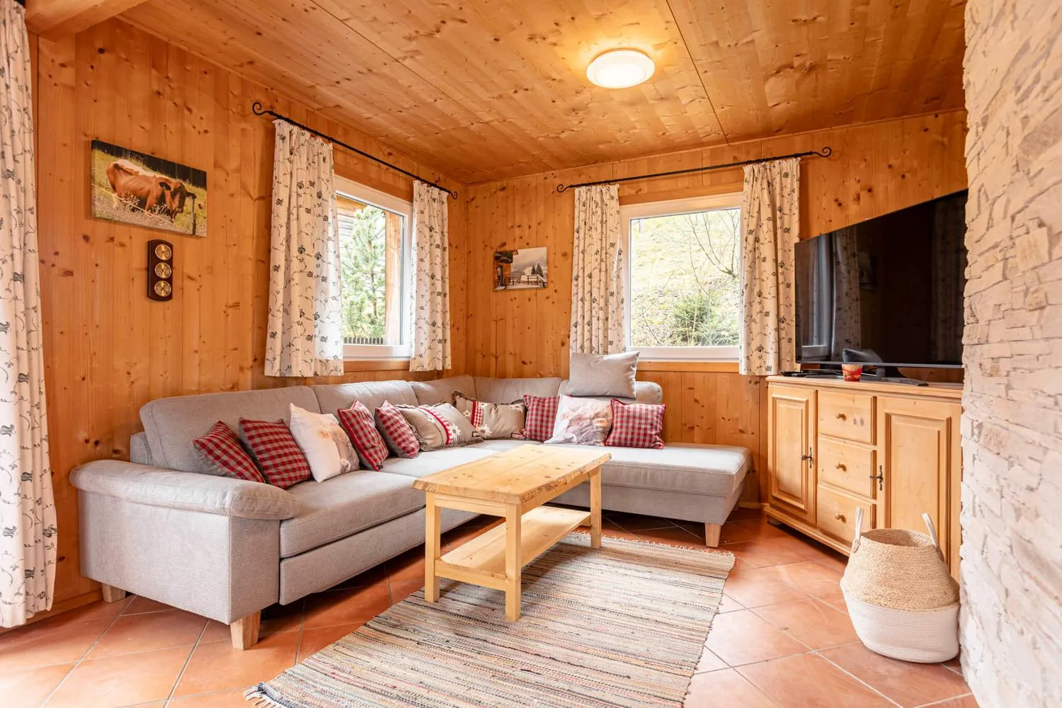 Rustikales Wohnzimmer mit grauer L-Couch und Holzverkleidung