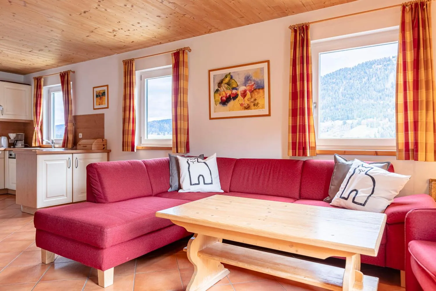 Geräumiges Wohnzimmer mit rotem Ecksofa und Bergblick aus Fenstern