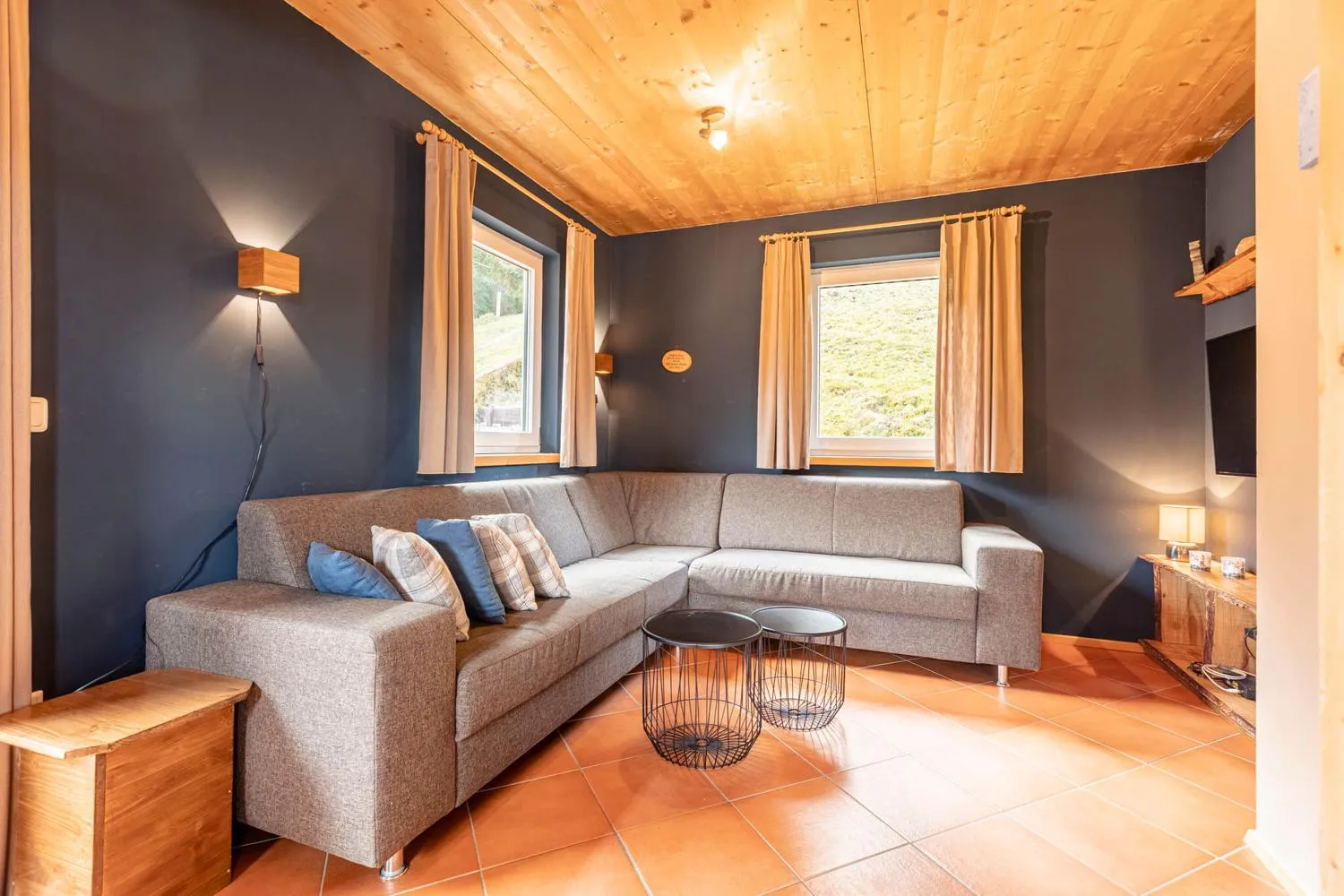 Modernes dunkles Wohnzimmer mit grauem L-Sofa und Wandleuchten