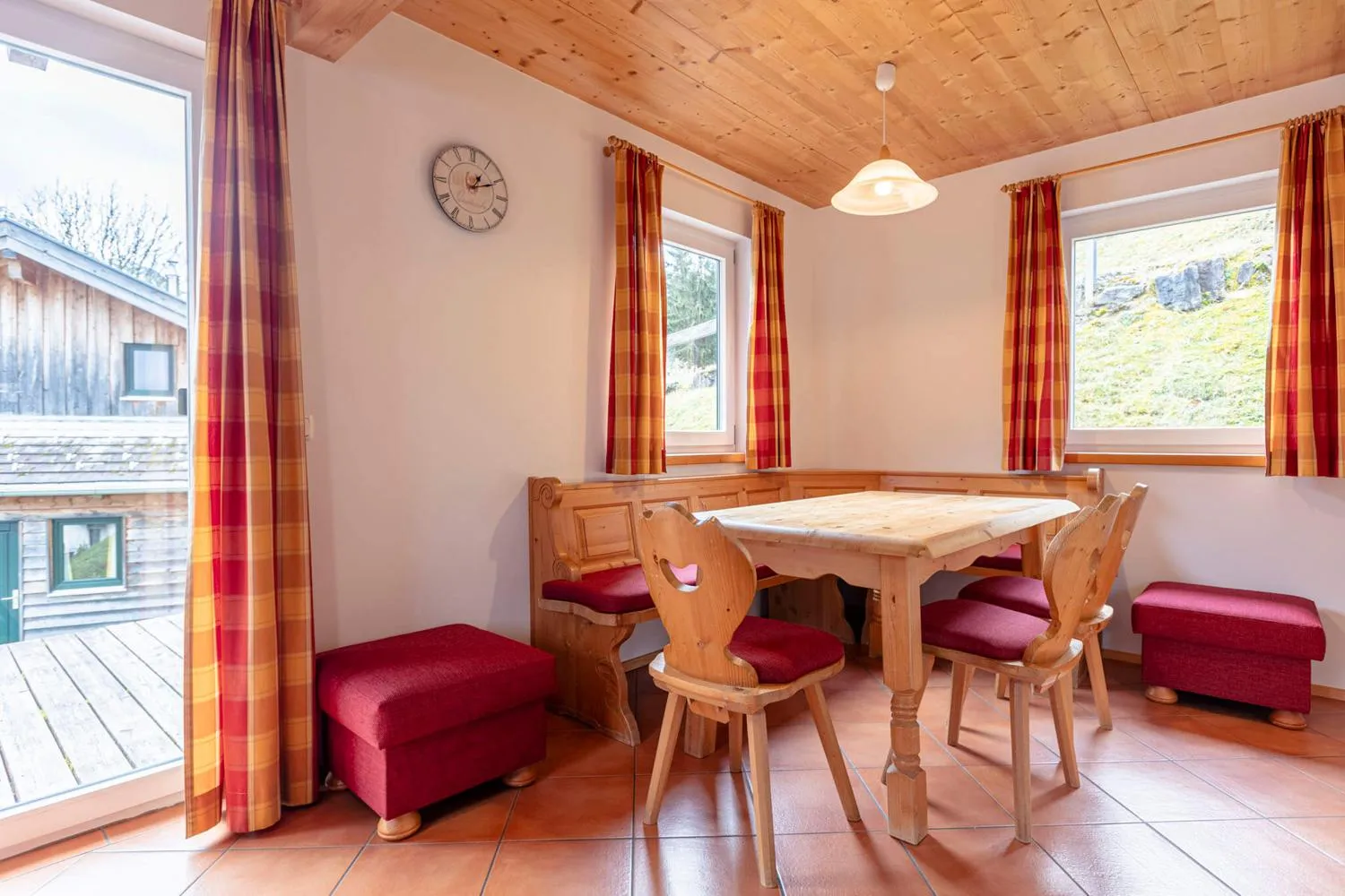 Esszimmer mit Holztisch und roten Sesseln, angrenzende Küche