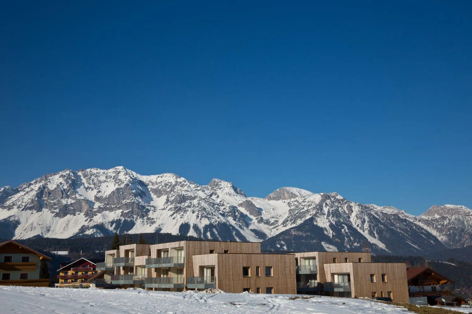 Alpenresort mit modernen Gebäuden vor schneebedeckten Bergen