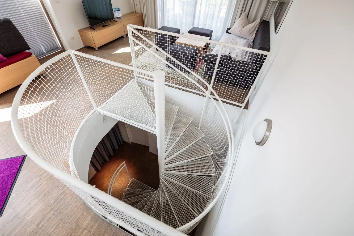 Spiraltreppe mit weißen Netzseitenwänden und Holzstufenanlage