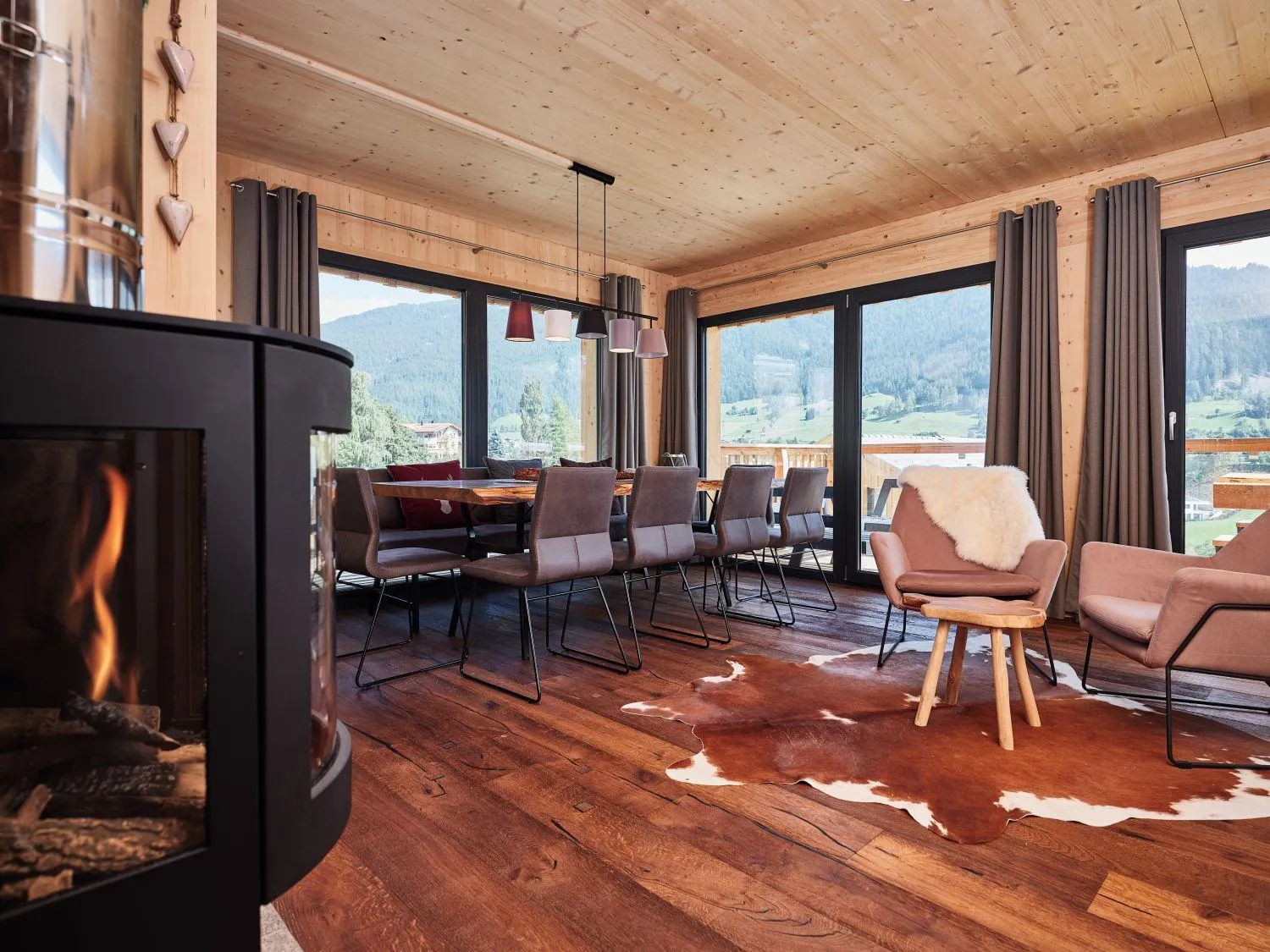 Esszimmer mit Panoramafenster auf Berglandschaft und schwarzem Kaminofen