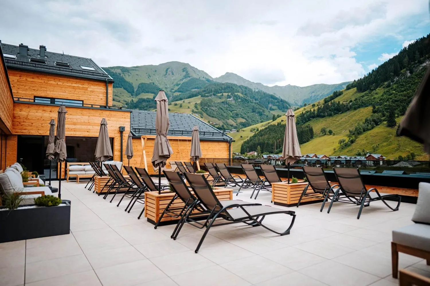Großer Wellness-Raum mit Holzdecke, Liegestühlen und Talblick
