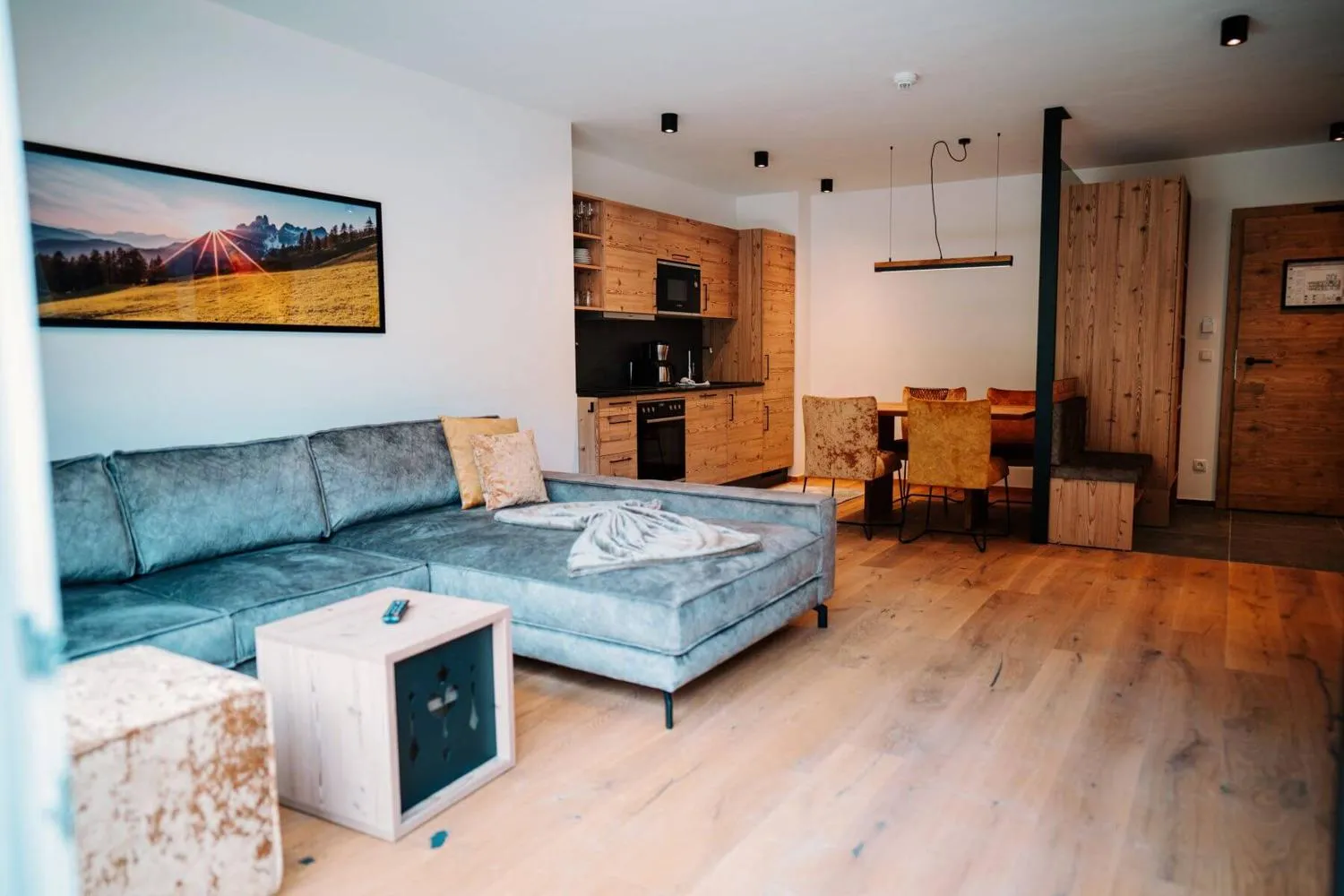 Wohnbereich mit Sofa, TV-Wand und offener Küchenzeile