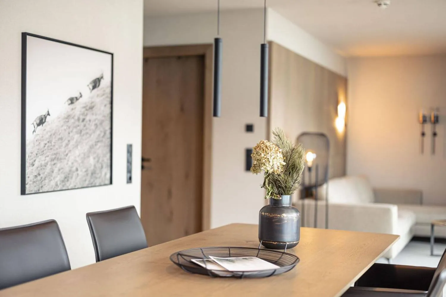 Esszimmer mit Holztisch, metallenen Hängeleuchten und Bergaussicht