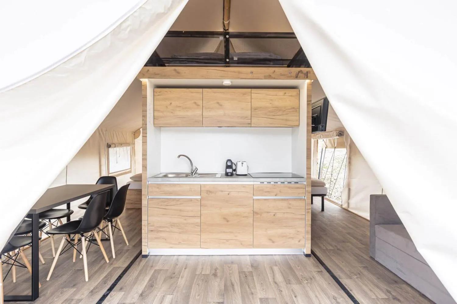Glamping-Pod mit erhöhtem Schlafbereich und kompakter Küche