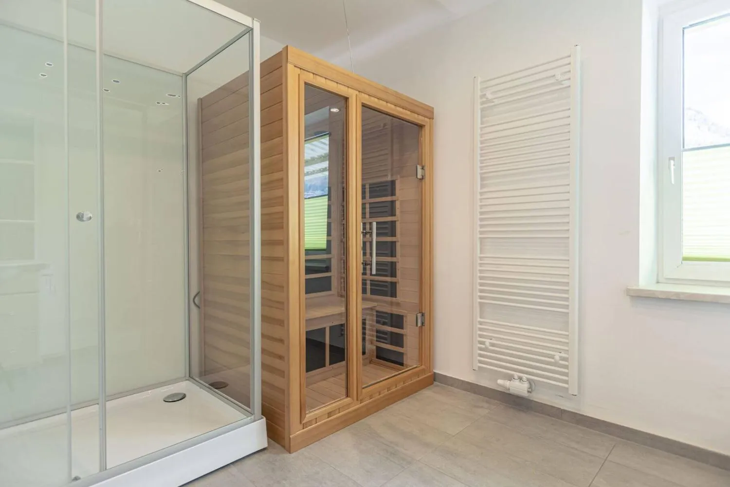 Badbereich mit Holzsauna und großer Glasdusche mit Fenster