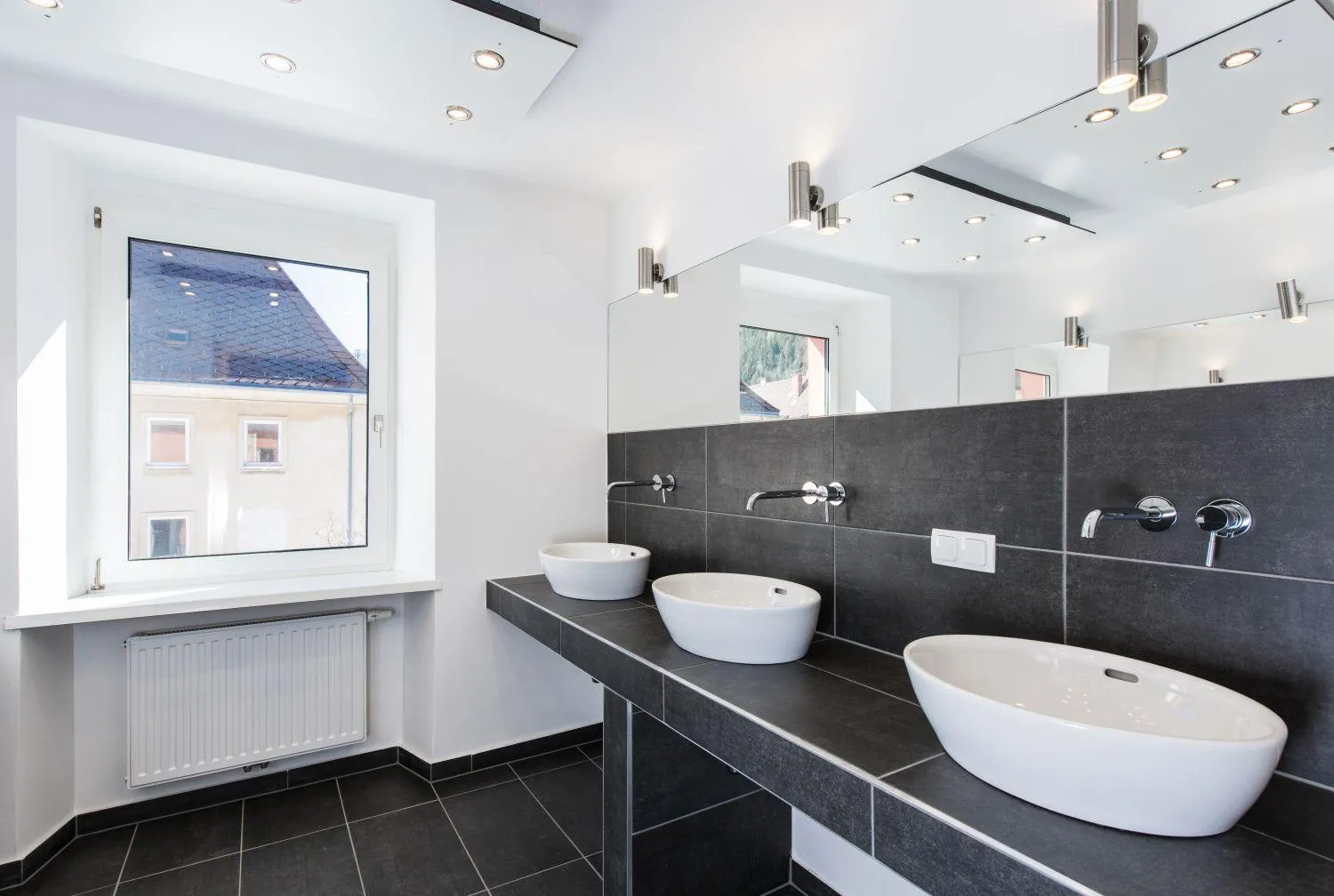 Modernes Badezimmer mit zwei weißen Waschbecken auf schwarzem Waschtisch