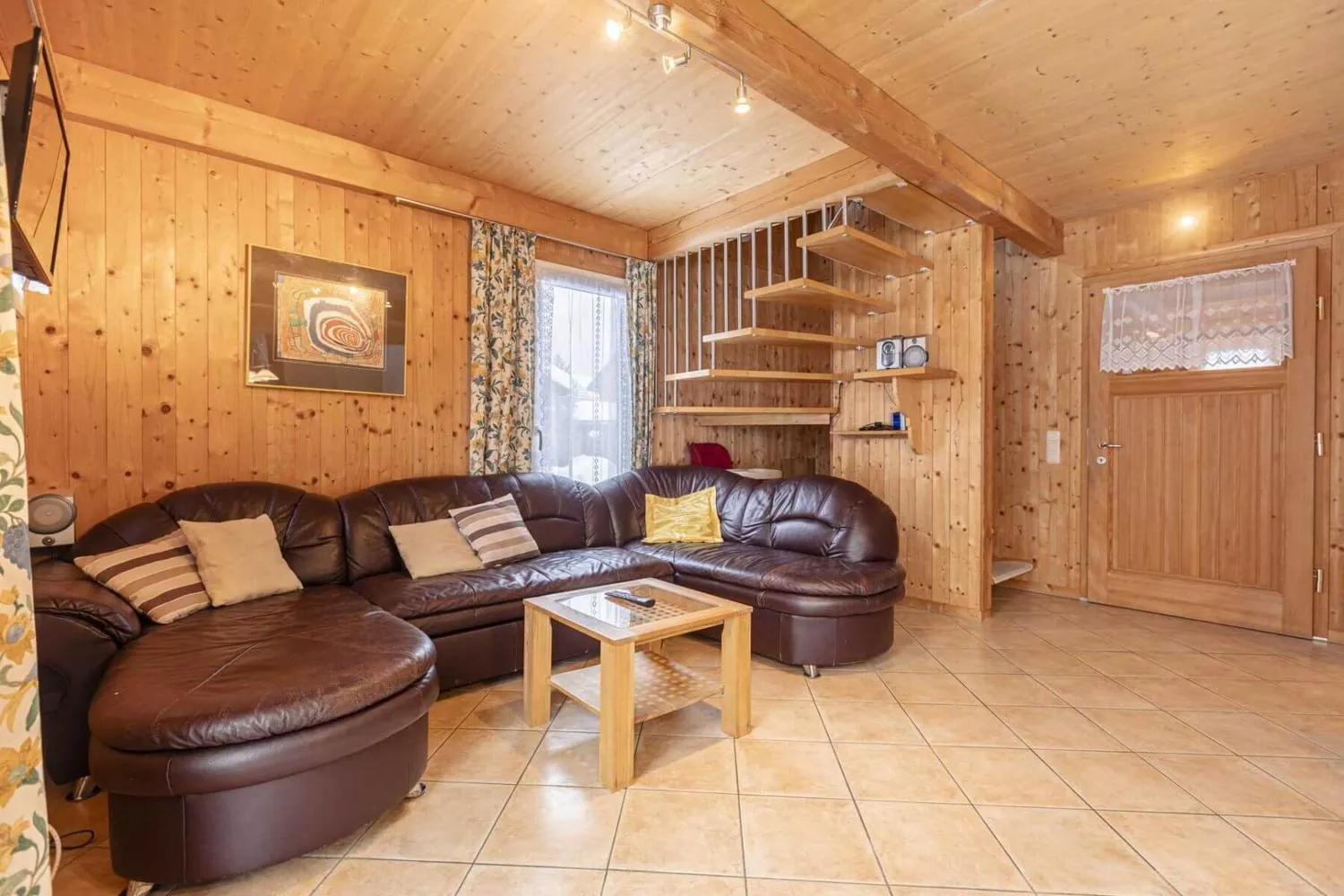 Holz-Wohnzimmer mit braunem Ledersofa und Wandregalen