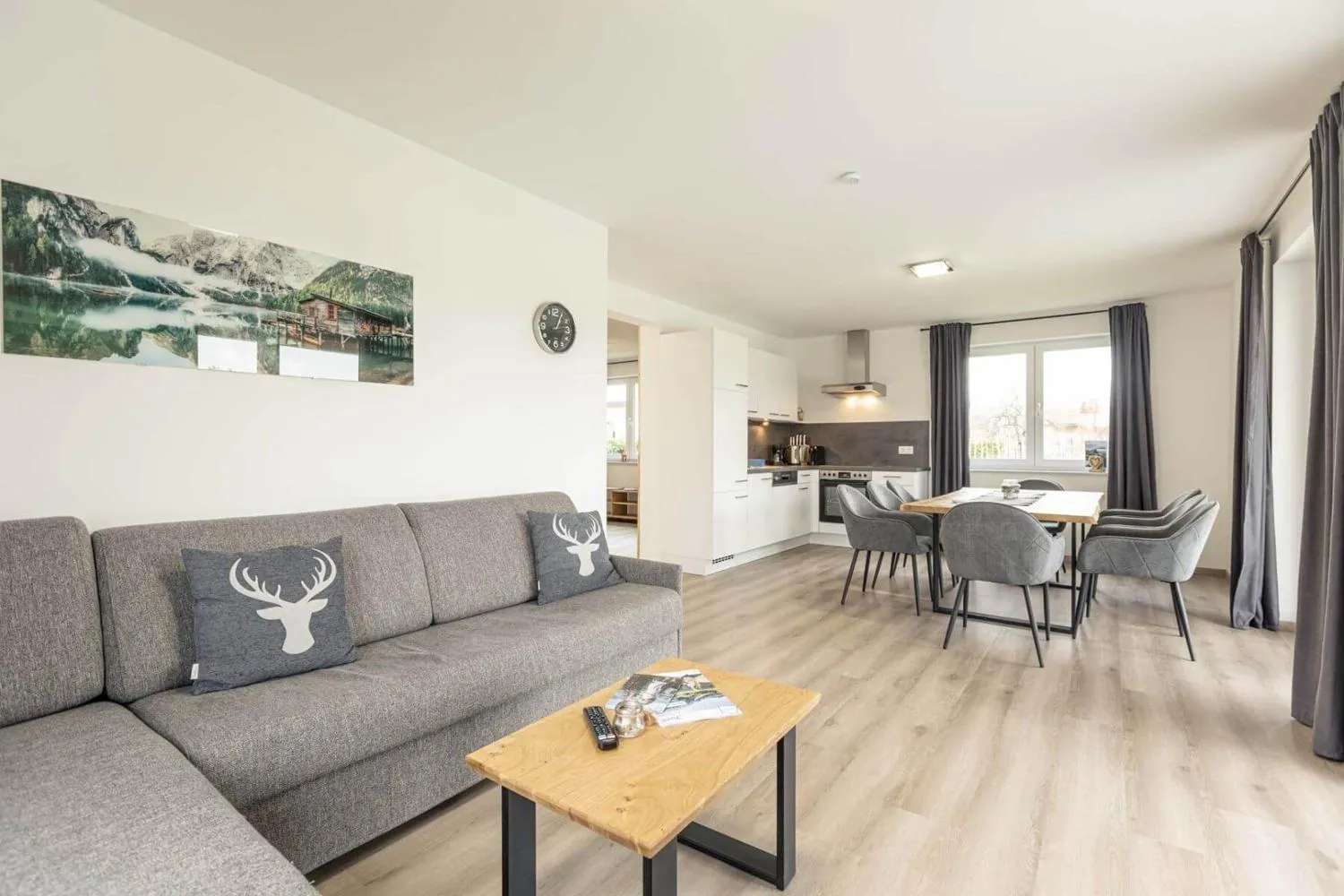 Wohnzimmer mit Sofa, Küchenzeile und Bergbild an Wand