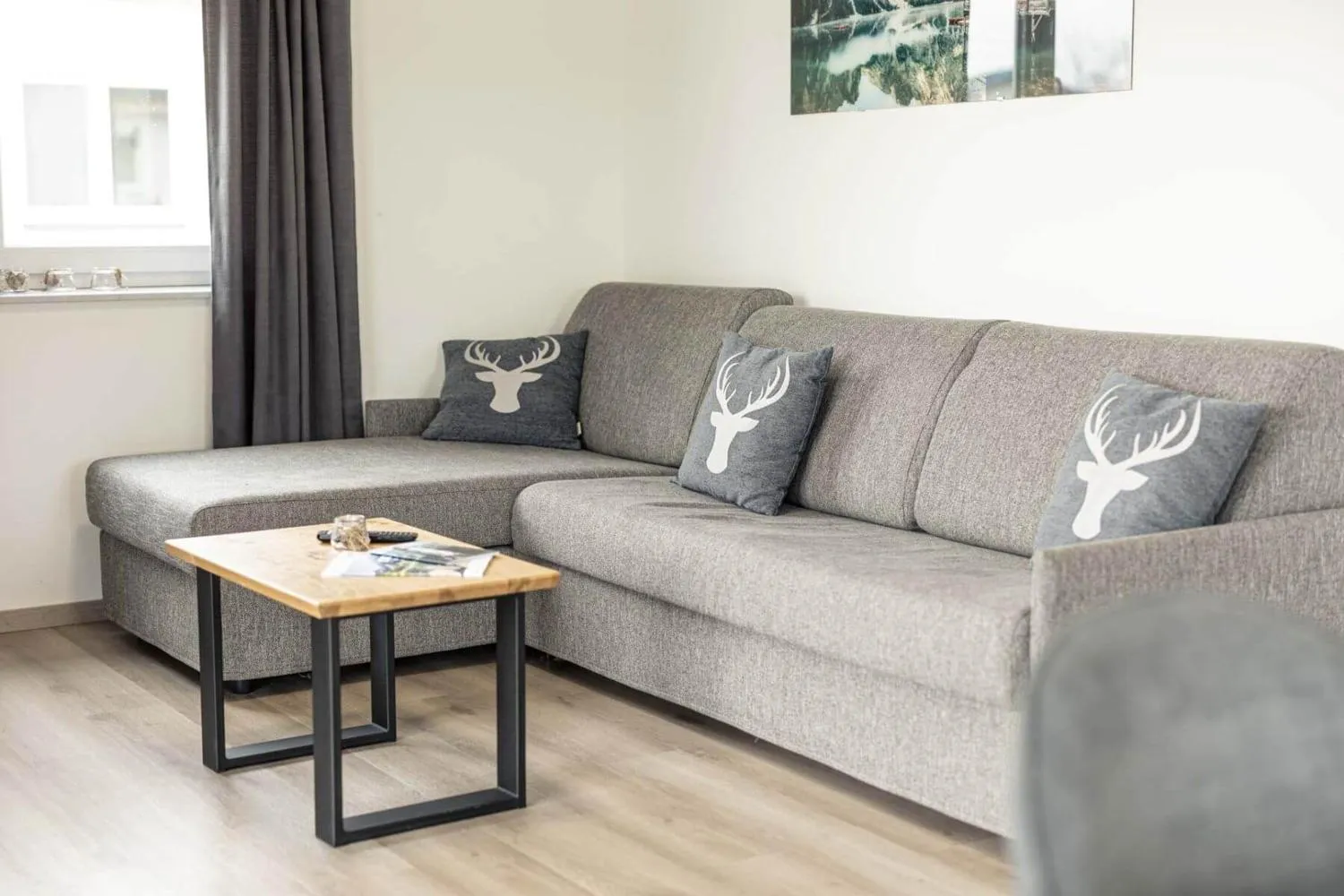 Graues Sofa mit Hirsch-Kissen und Holztisch
