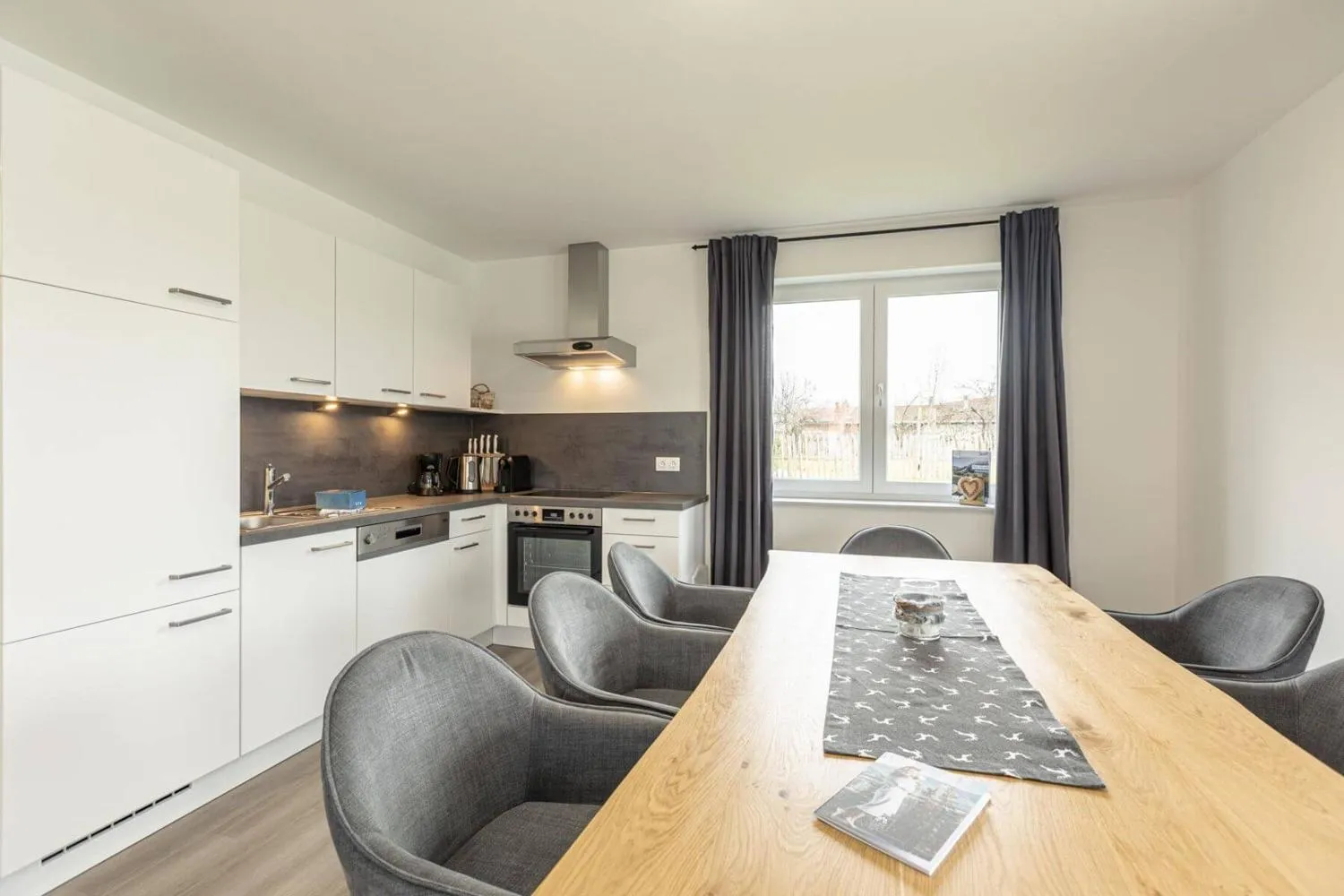 Moderne Küche mit weißen Schränken und Holztisch