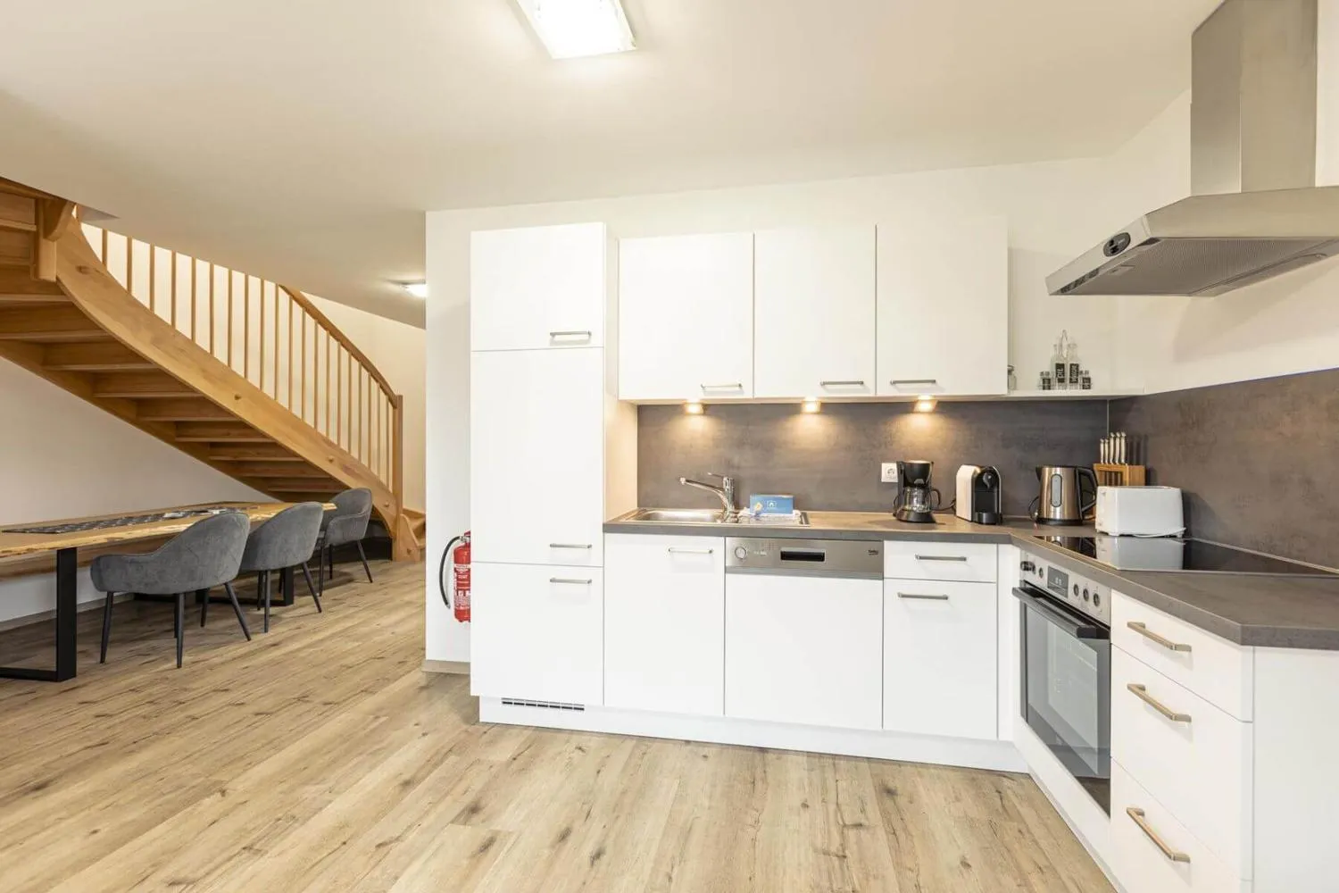 Offene Küche mit Holztreppe und kombiniertem Ess- und Wohnbereich