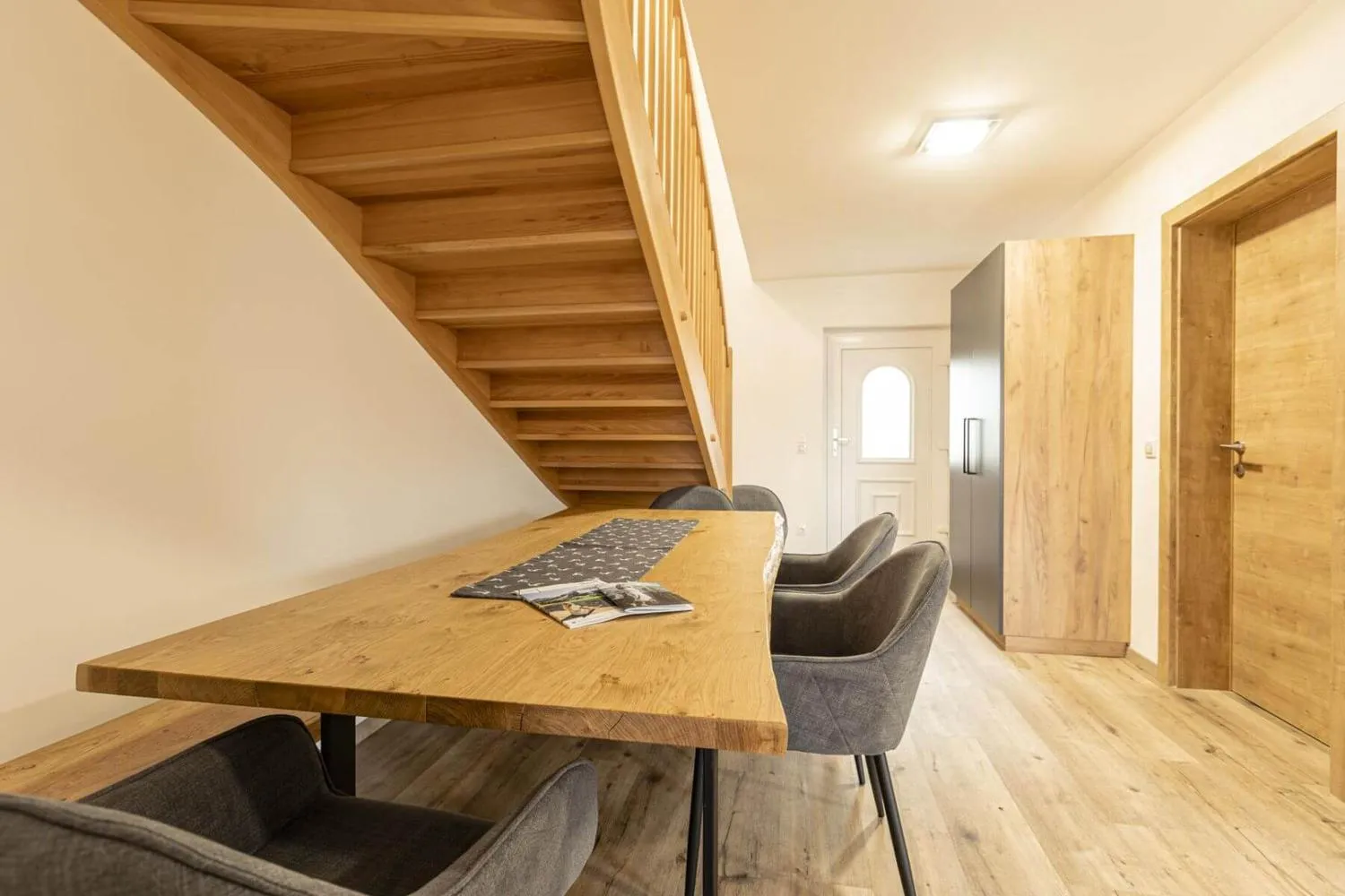 Holztreppe, Esstisch und Holztüren in offener Raumgestaltung