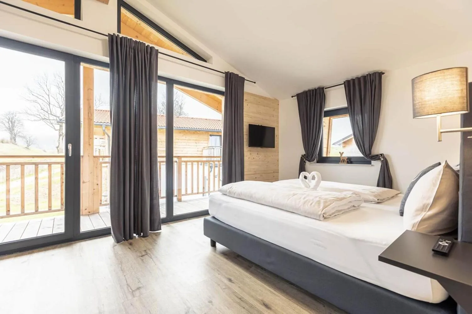 Schlafzimmer mit Balkon, modernem Bett und Berglandschaft
