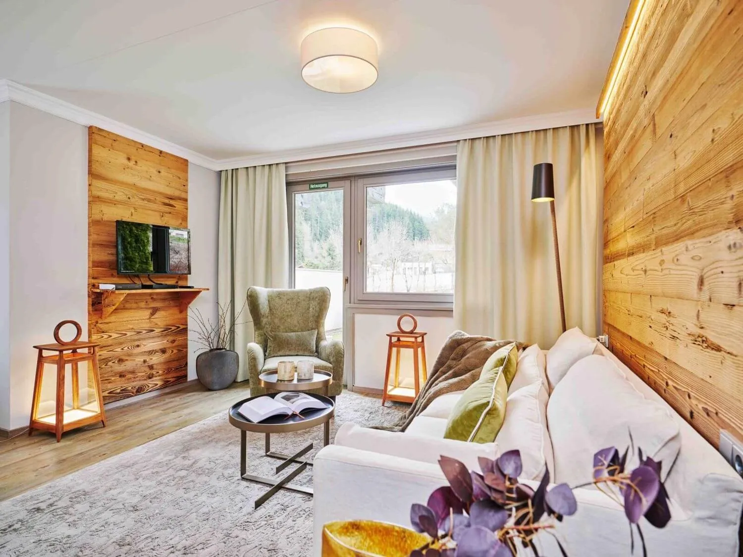 Suite-Wohnzimmer mit Holzwand, TV und Bergblick
