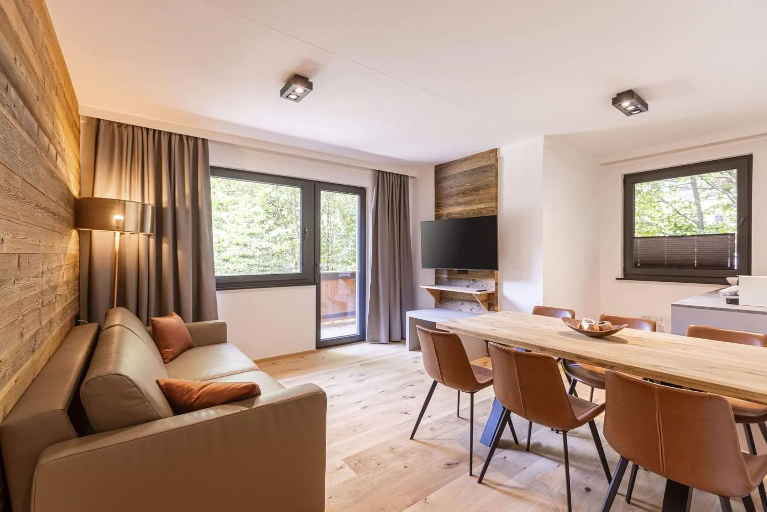 Offenes Wohnzimmer mit Sofa, Esstisch und Holzelementen