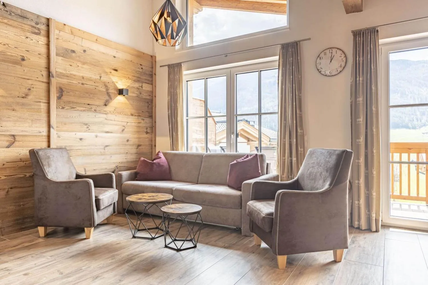Gemütliches Wohnzimmer mit Holzwand, Sesseln und großem Bergfenster