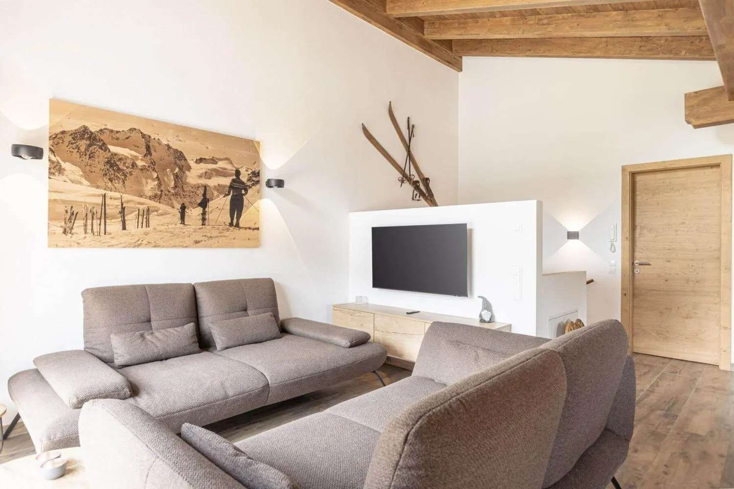 Wohnbereich mit Sofa, Flachbildschirm und Bild von Skifahrern an der Wand