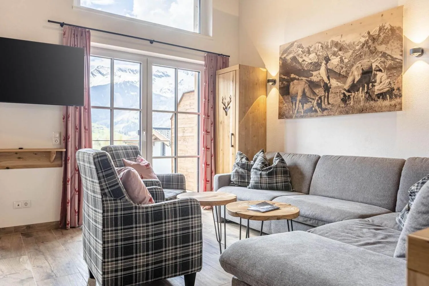 Wohnzimmer mit Sessel, Sofa und Blick auf schneebedeckte Bergkette