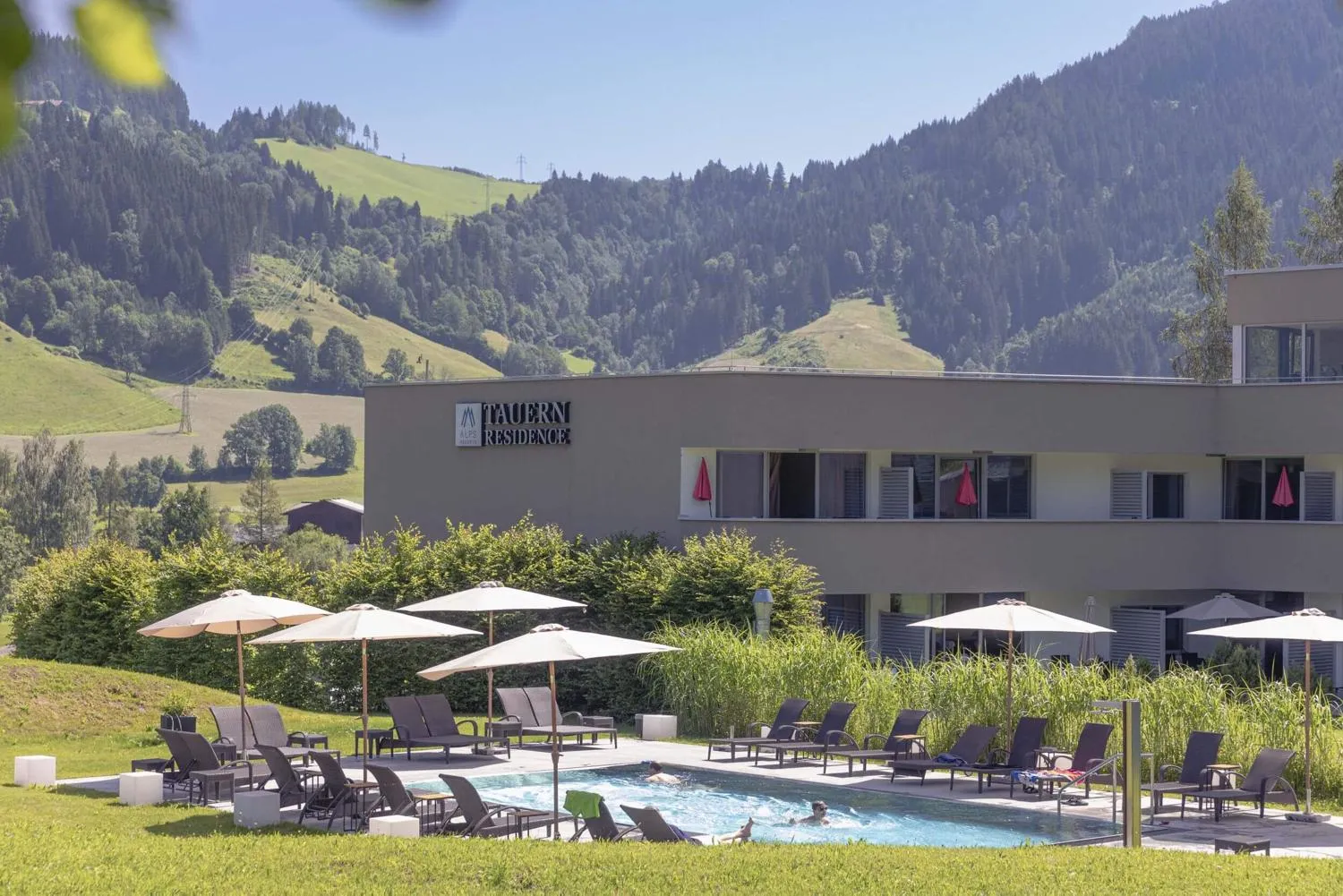 Außenpool mit Liegestühlen und Sonnenschirmen mit Bergblick