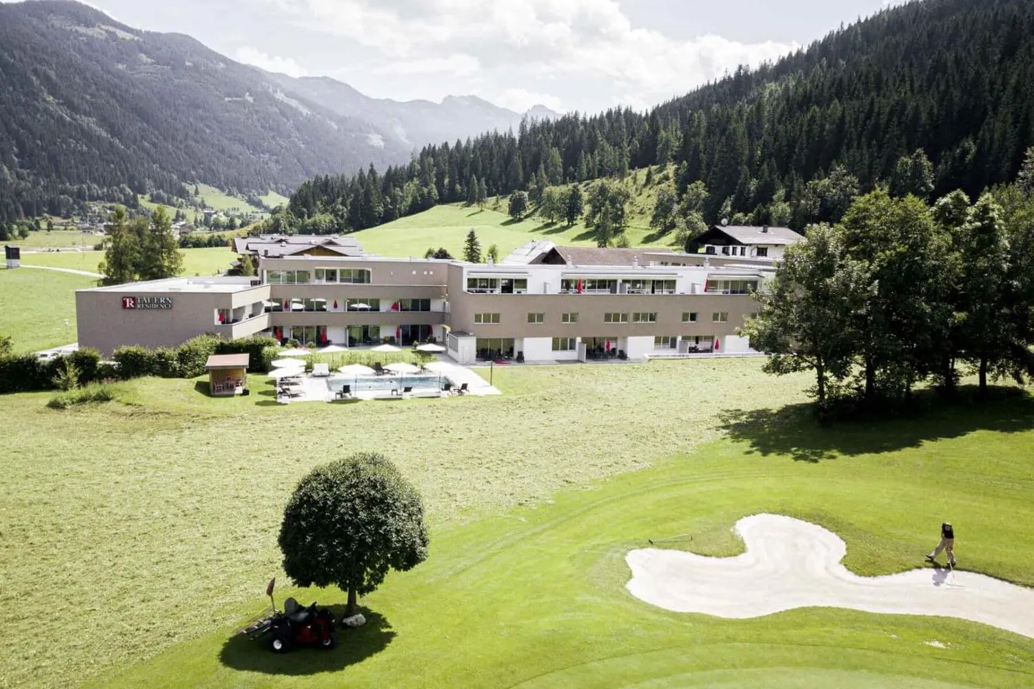 Resort neben Golfplatz mit Waldberghängen im Hintergrund