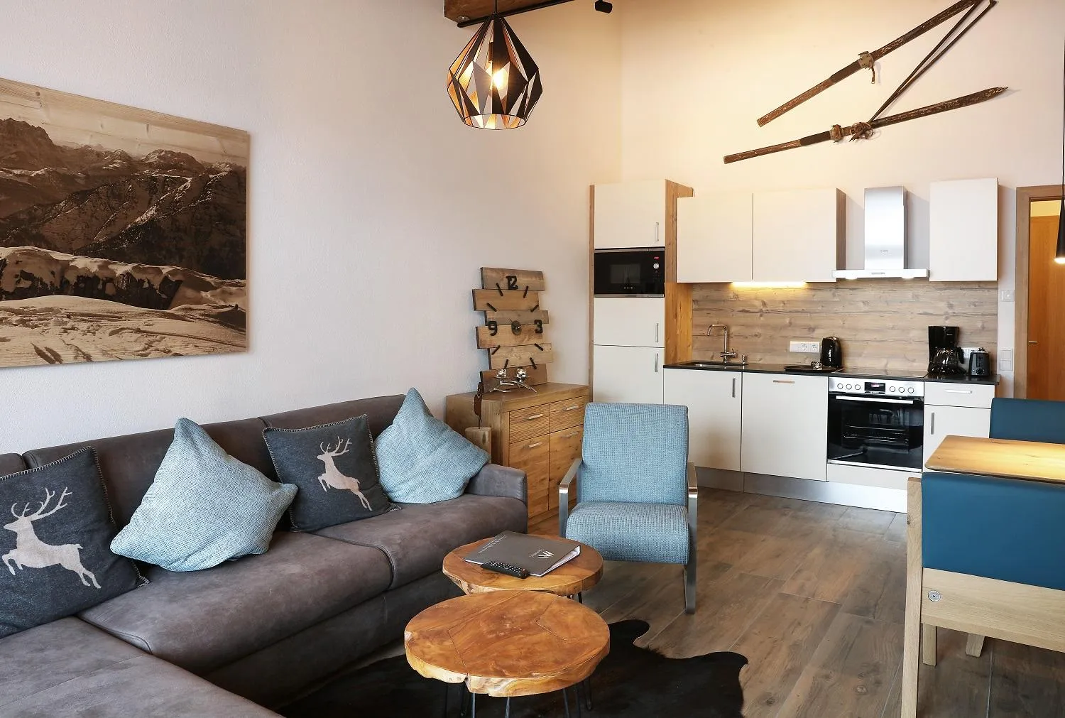 Wohnbereich mit grauem Sofa, Küche und Hirsch-Motiven
