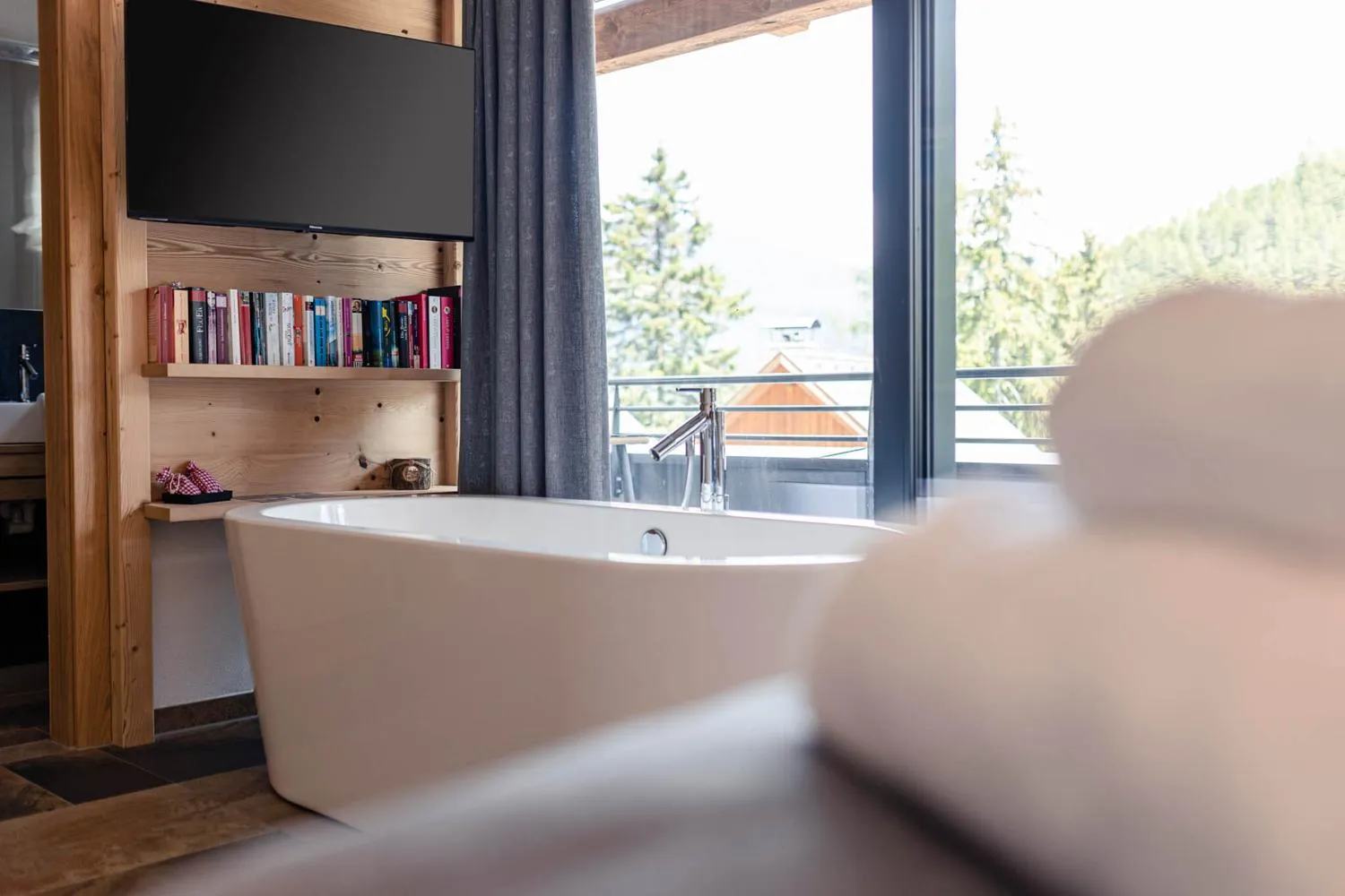 Modernes Badezimmer mit freistehender Badewanne und großem Fenster zum Berg