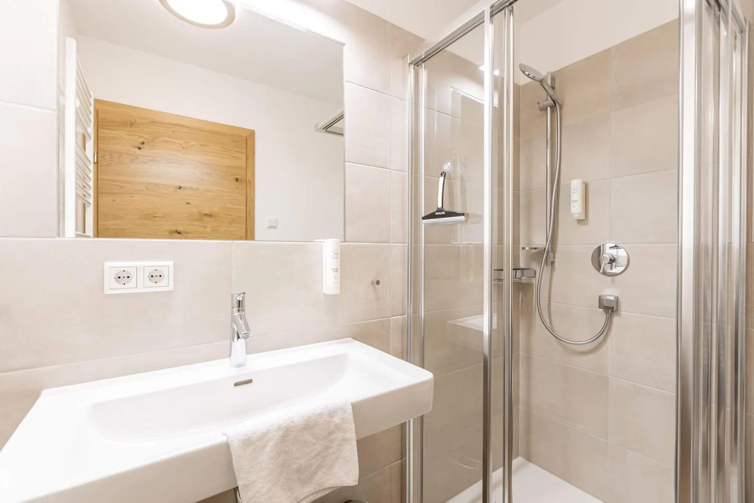 Helles Badezimmer mit Dusche, Waschbecken und Holz-Wandakzenten
