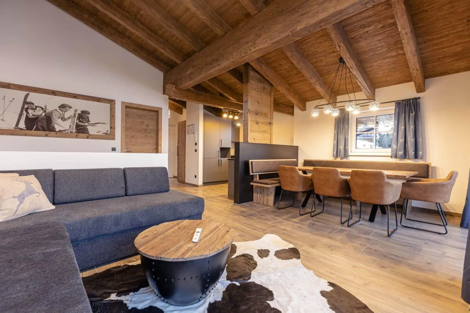 Großzügiges Wohnzimmer mit grauem Sofa, Couchtisch und Balkendecke