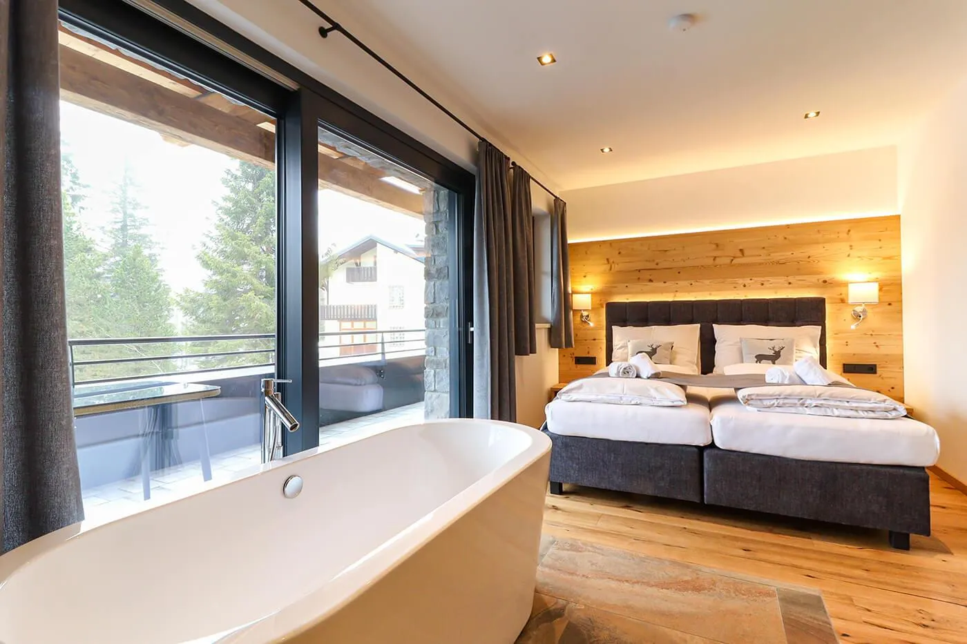 Luxus-Schlafzimmer mit freistehender Badewanne zum Fenster und Bergblick