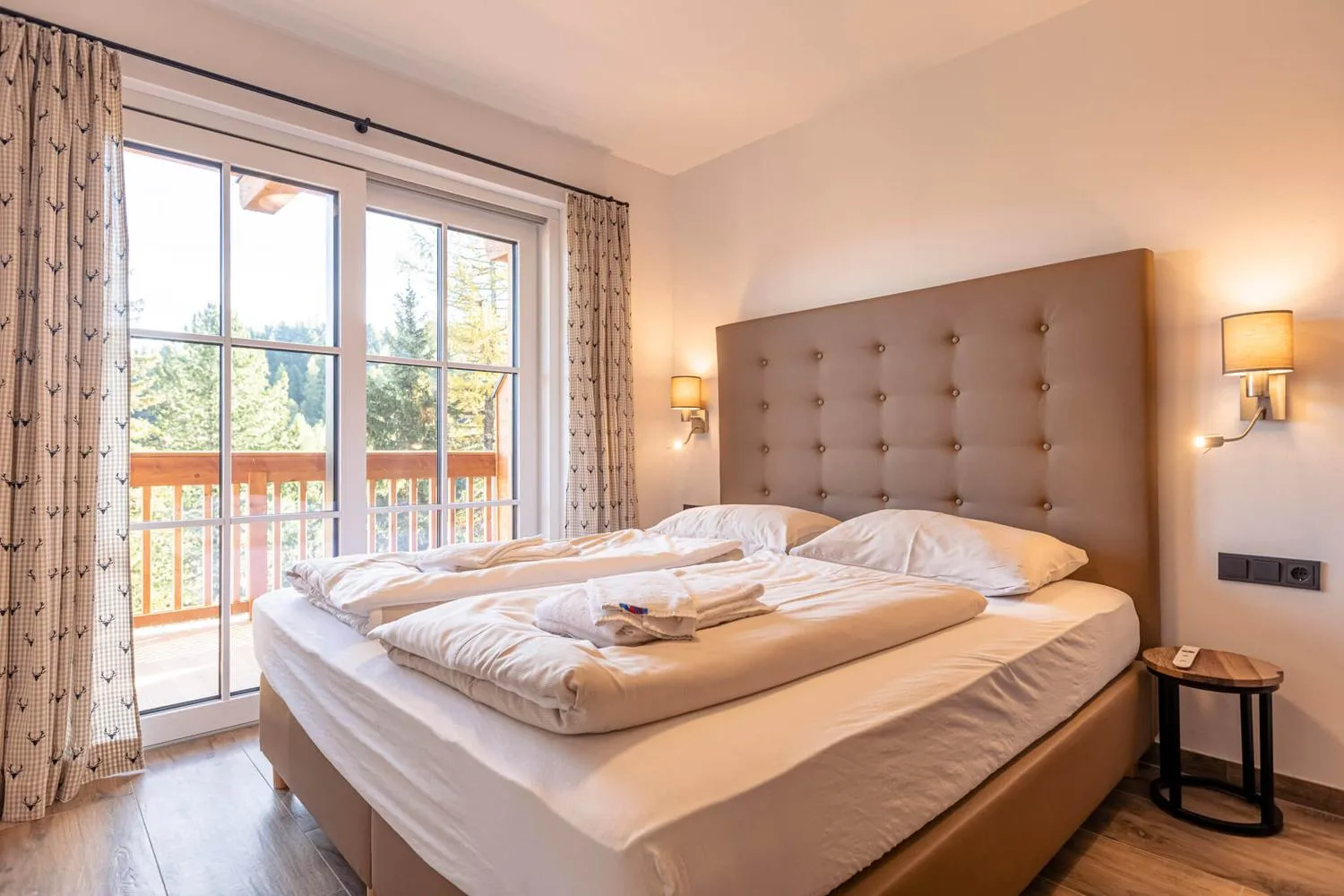 Schlafzimmer mit braunem Kopfteil, Balkonzugang und Bergaussicht