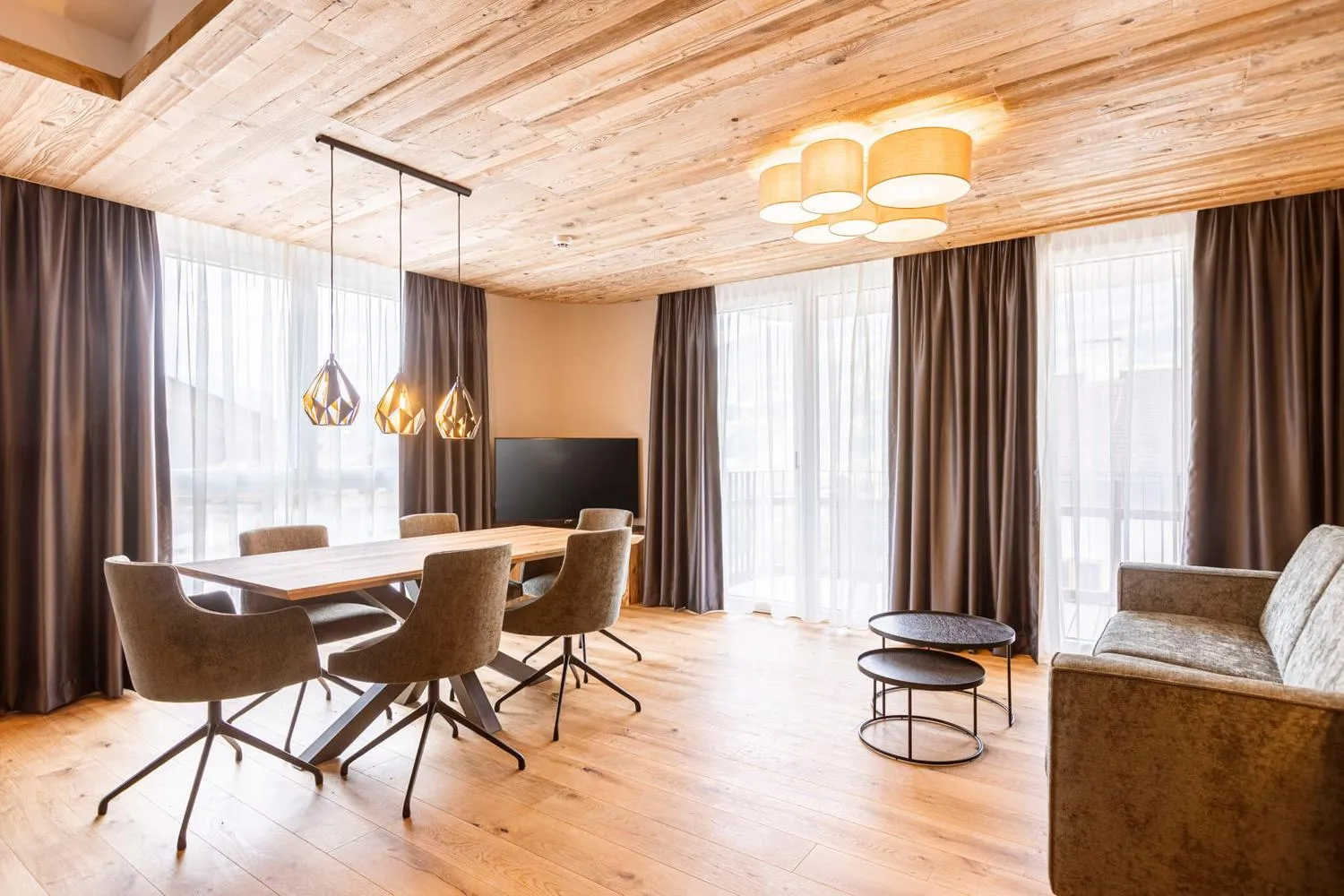 Modernes Wohnzimmer mit Holzdecke, Esstisch, Sofa und Erkerfenstern