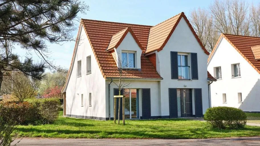 Weißes Ferienhaus mit Terrakottadach und dunkelblauen Fensterläden im Frühling