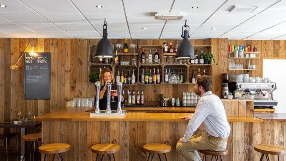 Rustikale Holzbar mit Getränkeregal und Bartender
