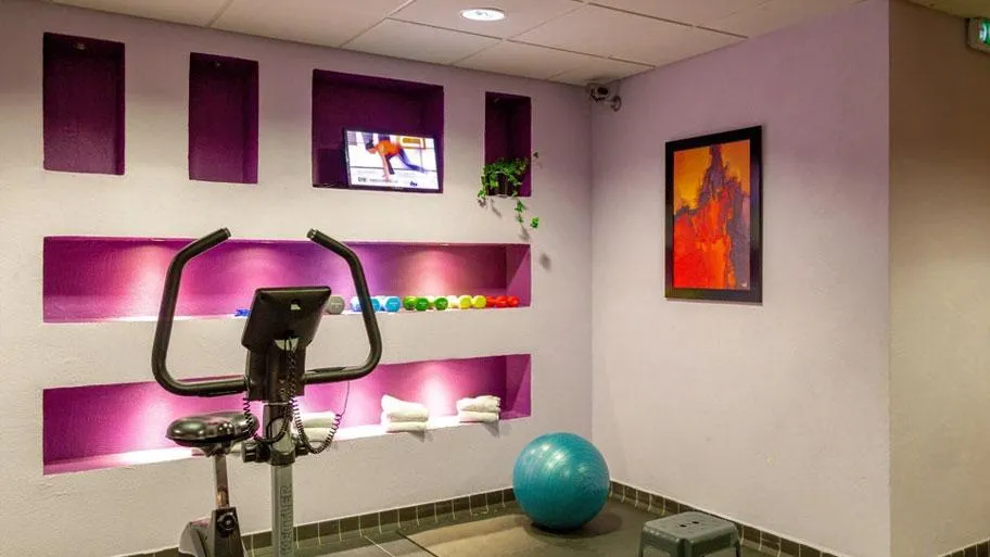 Fitnessstudio mit Ergometer, Gymnastikball und Wandgestaltung