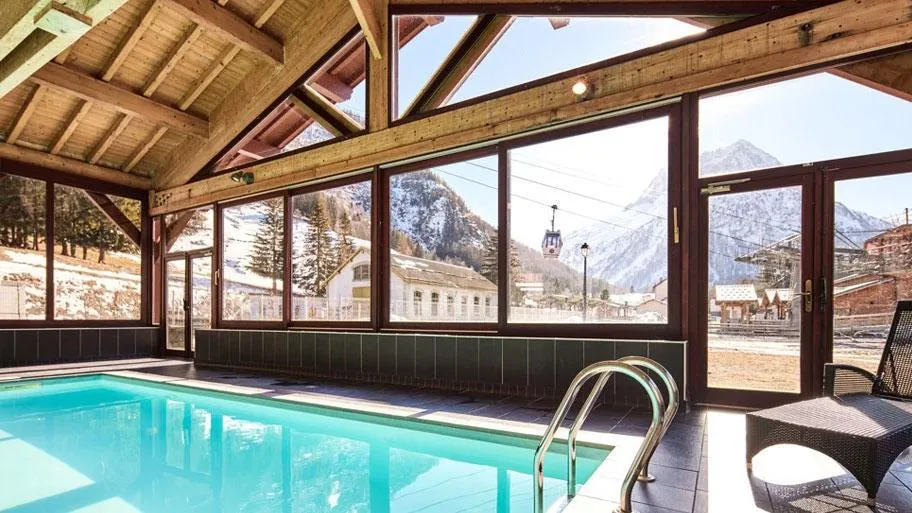 Hallenbad mit Glasdach und Ausblick auf schneebedeckte Berge