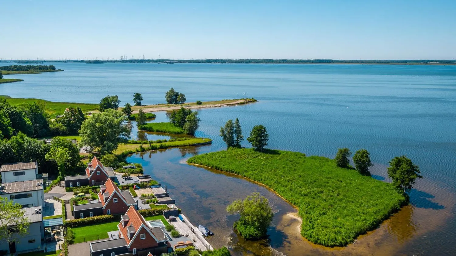Bootfahrer auf dem See mit Ferienhäuschen und roten Dächern