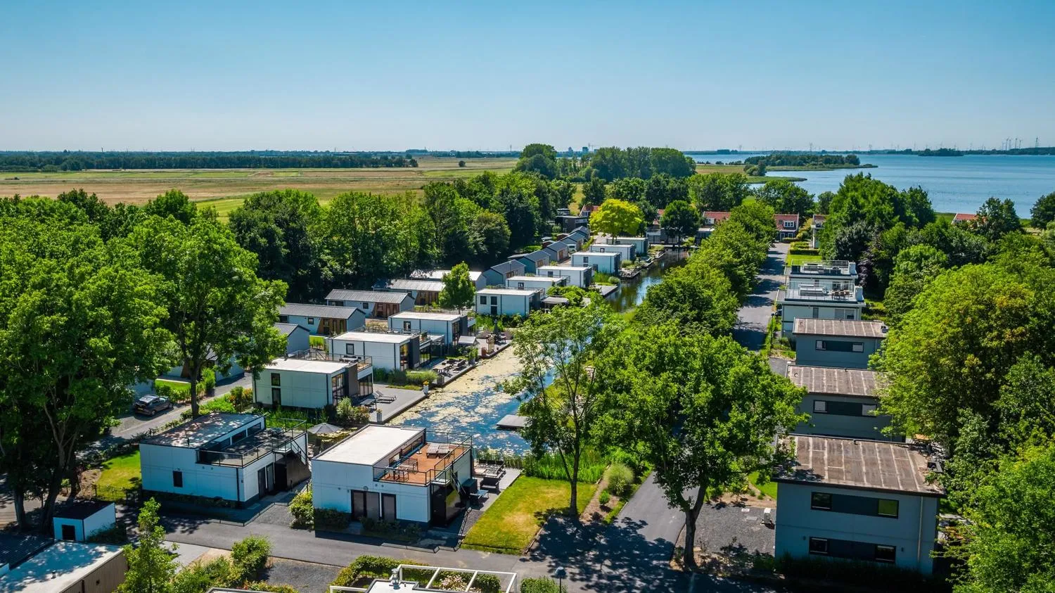 Ferienhäuser mit roten Dächern an grünen Ufern eines Sees