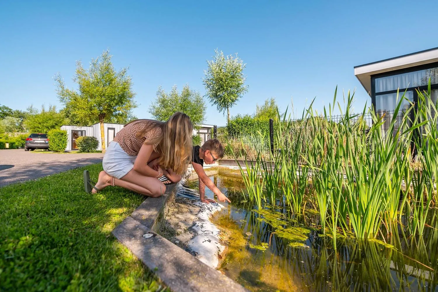 Erwachsener und Kind erforschen Tümpel im Park
