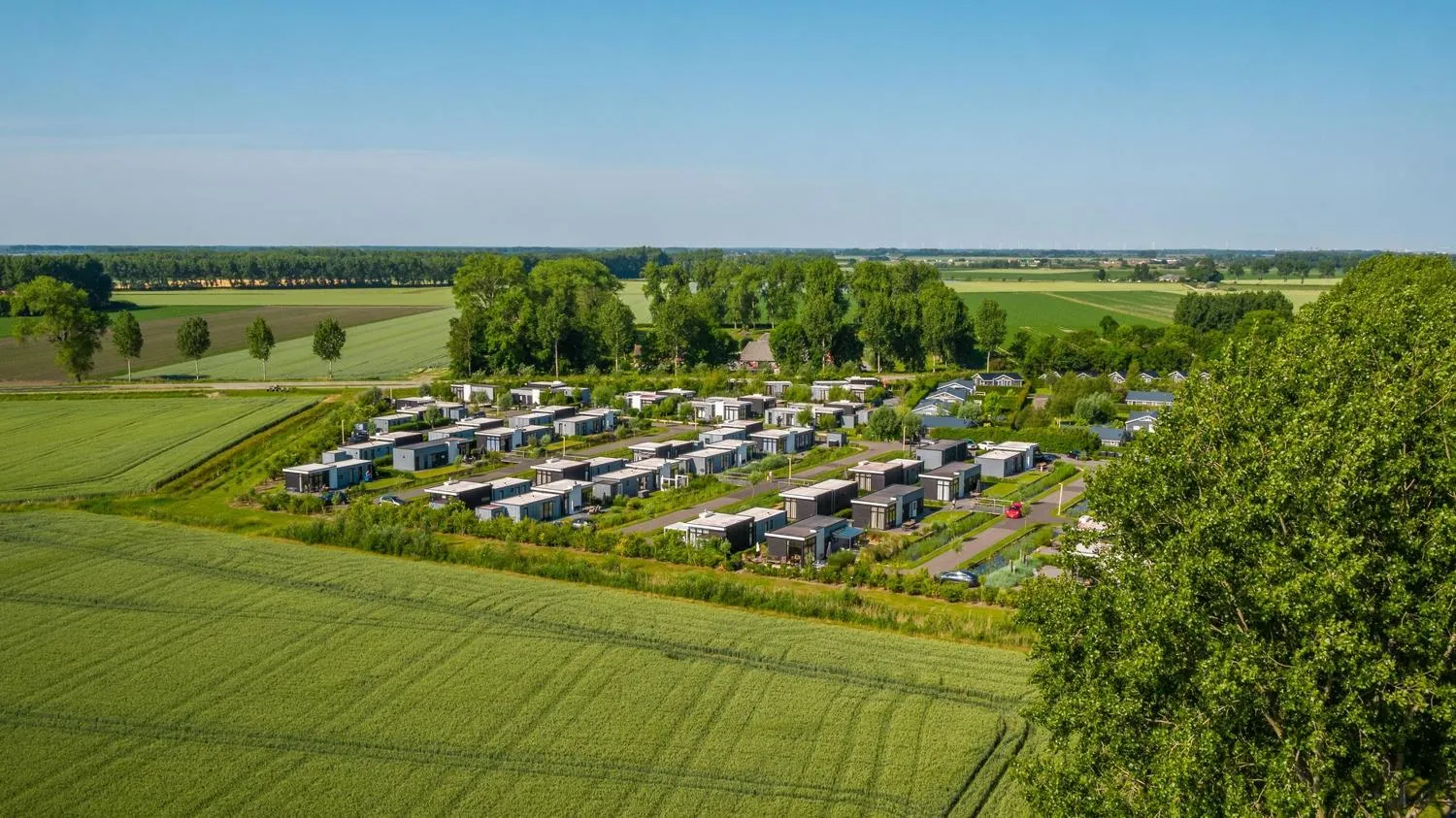 Moderner Ferienpark zwischen Ackerflächen und Baumreihen