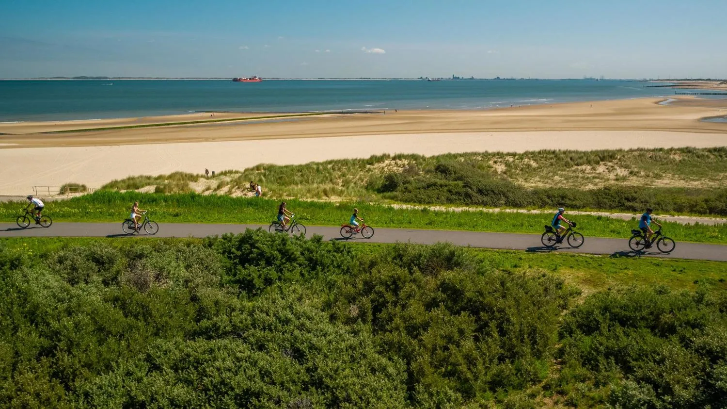 Fahrradfahrer auf Weg am Strand mit Dünen