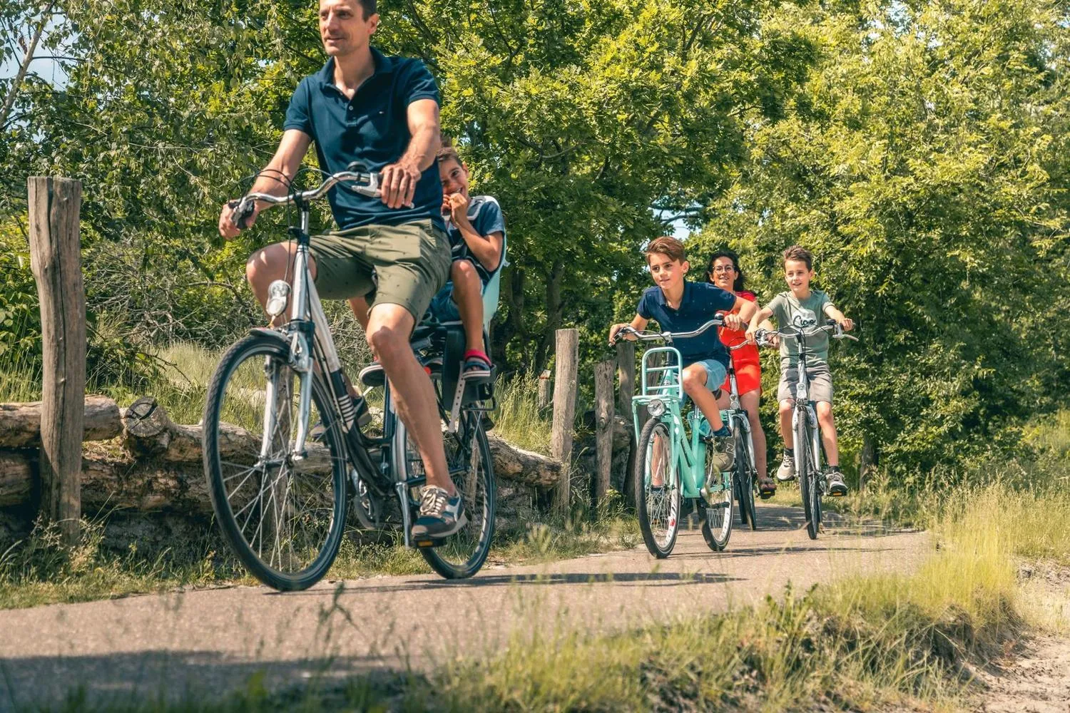 Vater und Kinder fahren auf Fahrrädern durch Waldweg