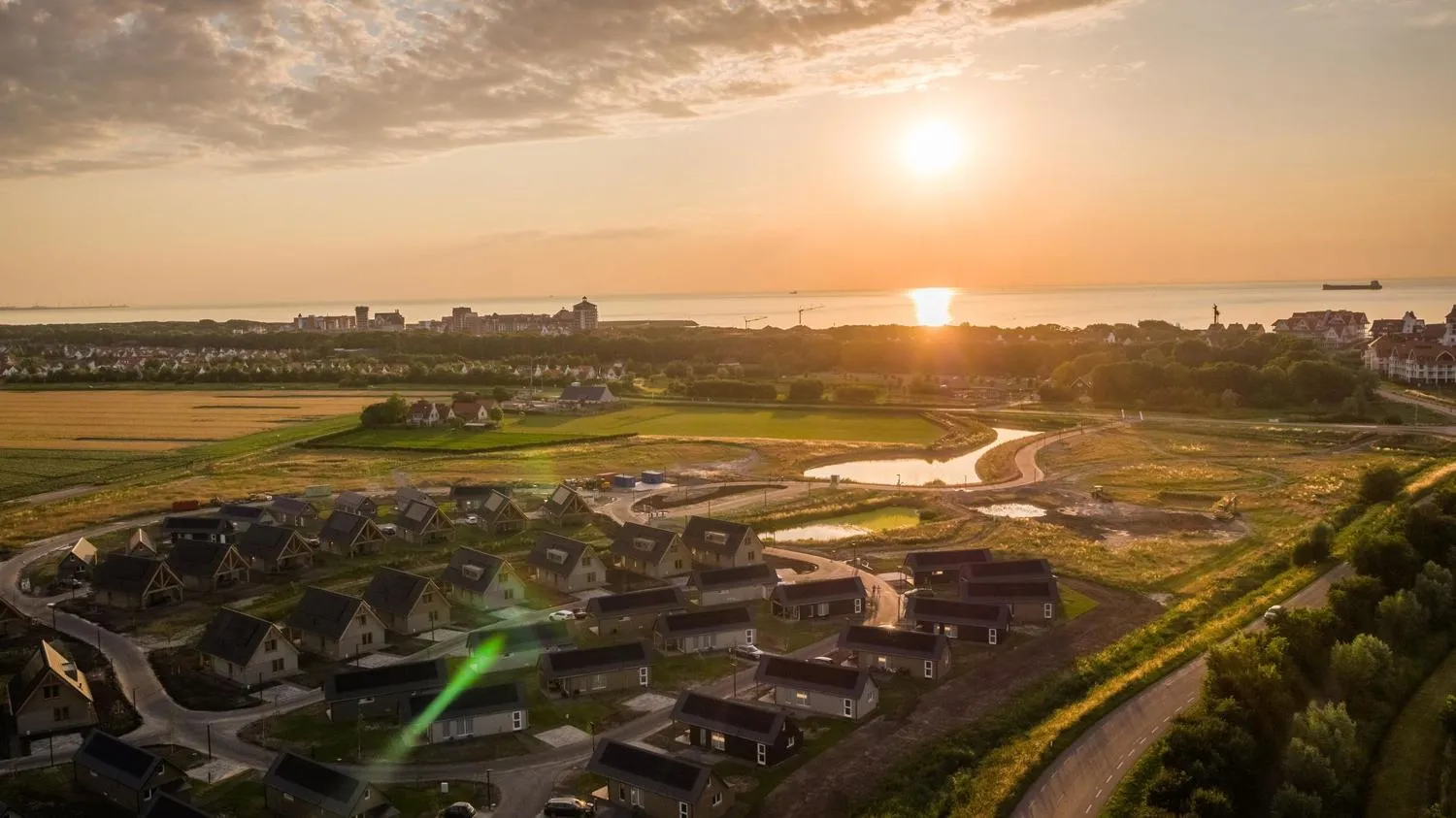 Sonnenuntergang über Ferienpark mit modernen Häusern und Wiese