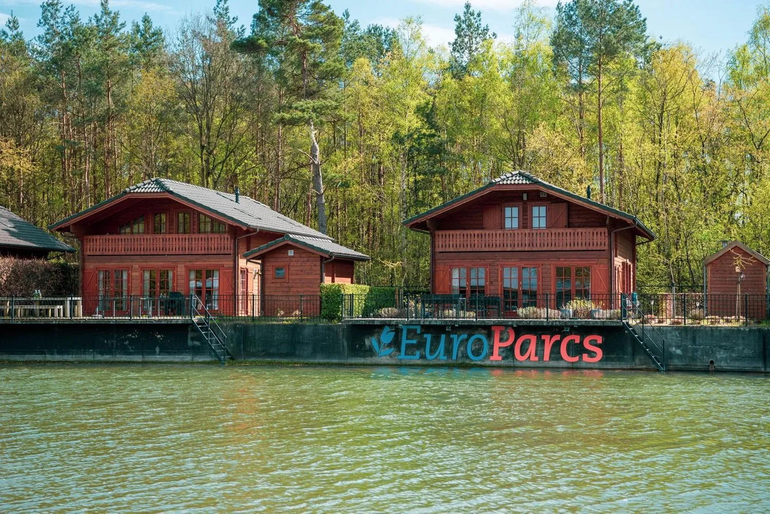 Rote Holzhäuser am Wasser mit EuroParcs-Schriftzug auf schwarzem Kai