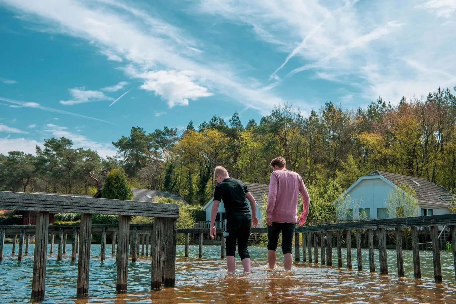 Holzsteg über dem See mit Blick auf Ferienpark und Waldkulisse